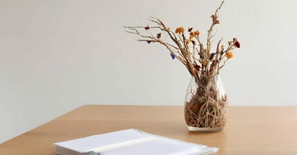 na biurku wazon z suchymi galazkami lub suszonymi kwiatami 